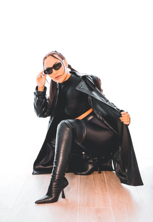 Free Stylish woman posing in black leather attire with sunglasses, exuding confidence and modern fashion. Stock Photo
