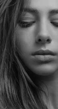 Close-up black and white portrait of a woman's face evoking deep emotion.