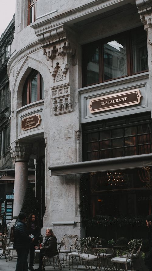 Free A charming outdoor seating area at a restaurant on a historic European street. Stock Photo