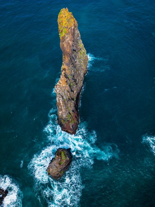 Free A stunning aerial view of the sea stack at Ribeira da Janela, Madeira, surrounded by vibrant blue ocean waves. Stock Photo