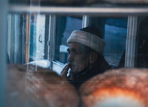 Free An elderly man smokes thoughtfully by a window in Istanbul, capturing a moment of reflection. Stock Photo
