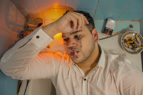 Young Depressed Man Smoking a Cigarette in a Bath