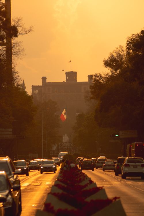 Free A vibrant urban scene in Mexico City with traffic and skyline silhouettes under a golden sunset. Stock Photo