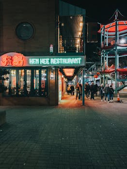 People walking by Ken Kee Restaurant under neon lights, capturing a lively city nightlife scene.