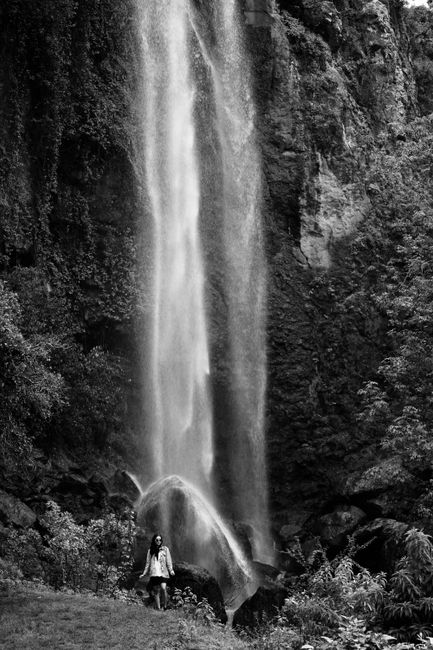 Breathtaking waterfall cascading down with a lone woman standing below, evoking the power of nature.