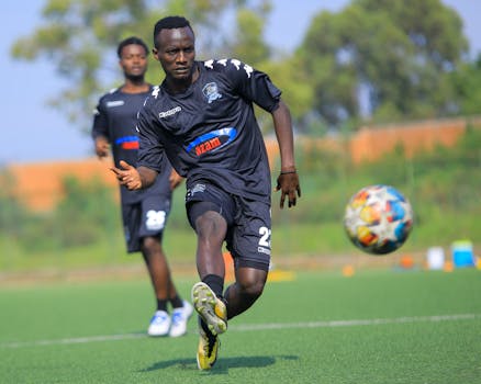 A soccer player in black sportswear actively playing on the field during the day.