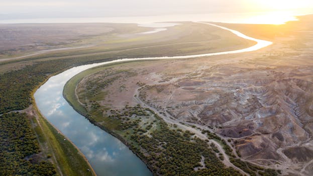 Stunning aerial view of a winding river through a barren landscape at sunrise, capturing natural beauty.