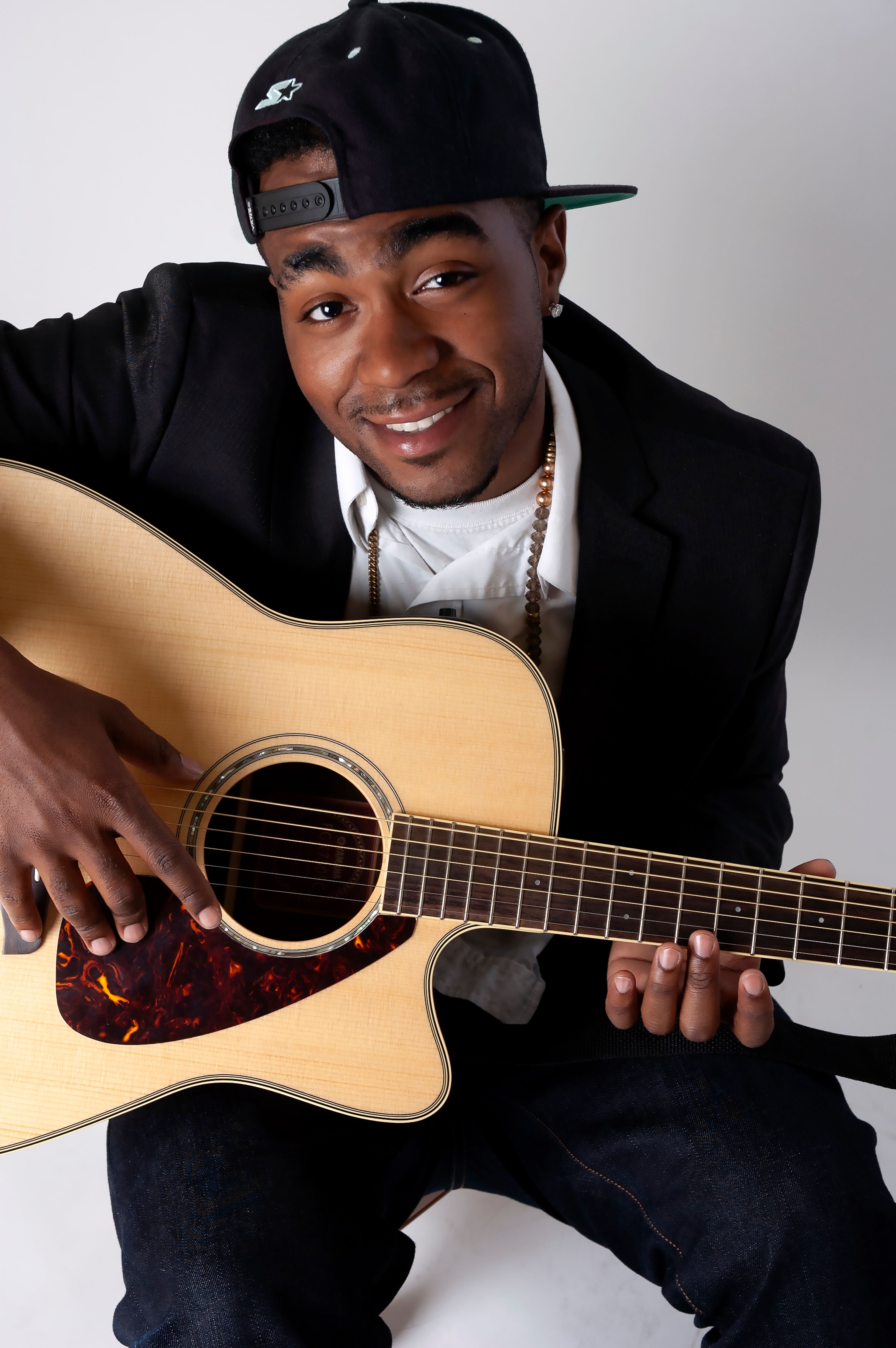 A cheerful young man plays acoustic guitar, capturing the joy of music.