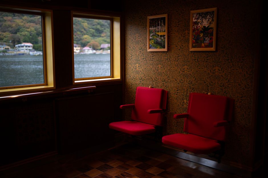Cozy interior of a ferry with red seats, overlooking Lake Ashi in Hakone, Japan.
