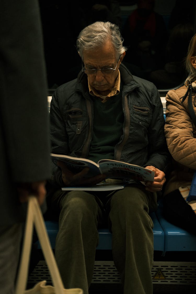 Old Man Reading In Subway Train