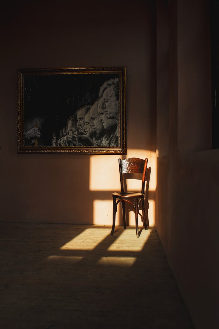 Empty Chair In Light In Room In Shadow