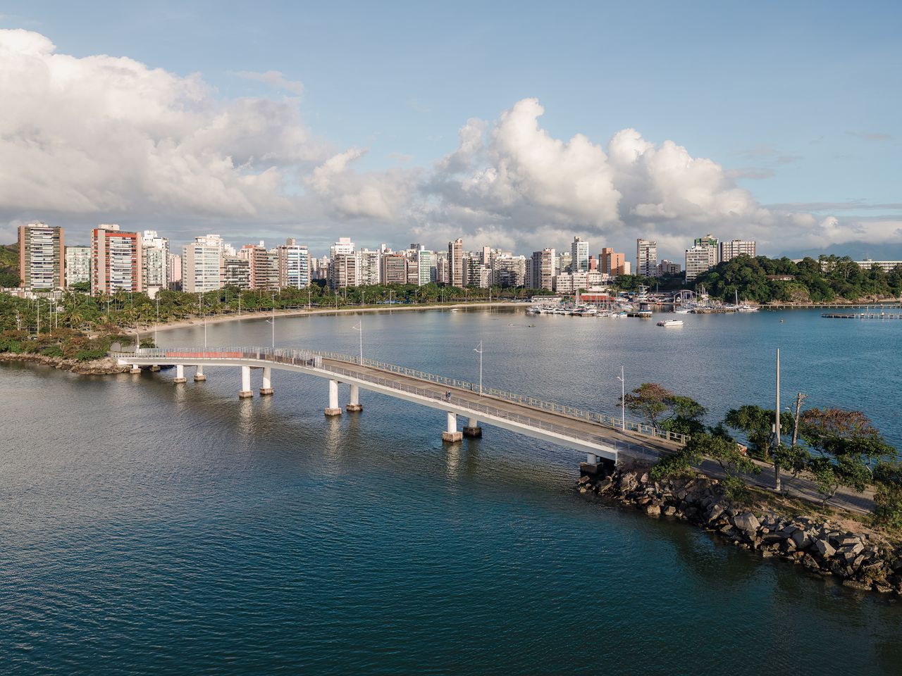 Stunning aerial view of Vitória, ES, Brazil, showcasing the cityscape and bridge over a tranquil body of water.