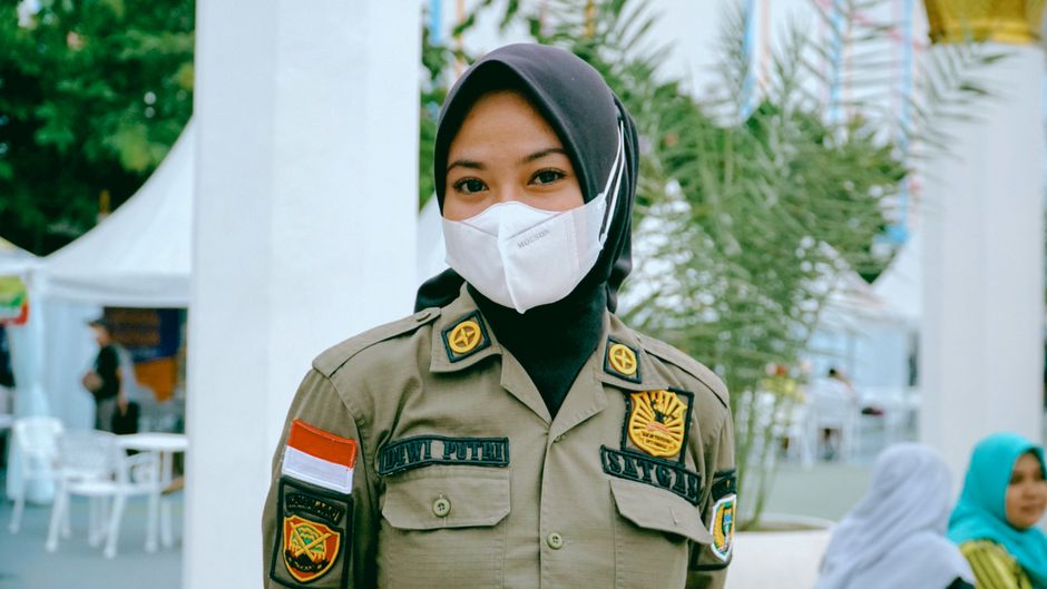 Portrait of an Indonesian officer in hijab and face mask, outdoors in Madiun.