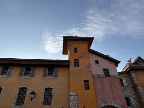 Low angle view of a rustic building with textured walls and tower against a clear blue sky.