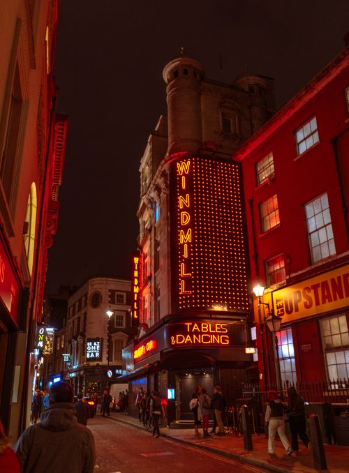 Free Illuminated buildings and neon signs light up a bustling city street at night, capturing urban nightlife. Stock Photo