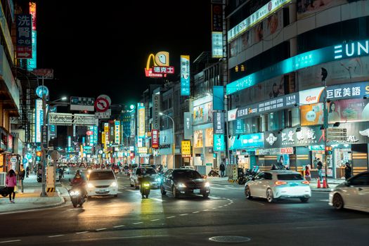 Lively city street at night with traffic and illuminated billboards in an Asian metropolis.