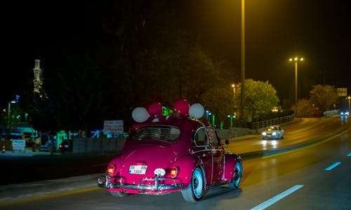 A Volkswagen Beetle with Balloons on a City Street at Night 