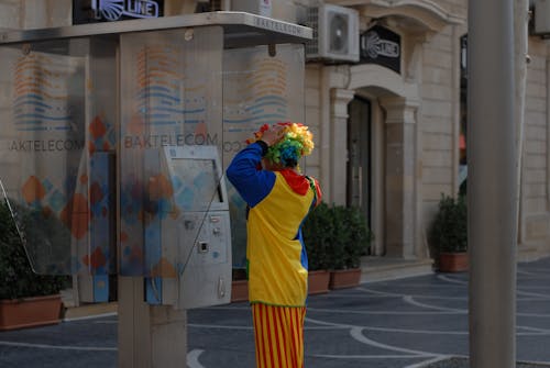 Clown Using a Public Phone in the City 