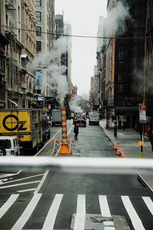 Free A bustling city street with steam rising and vehicles in traffic, showcasing urban life. Stock Photo