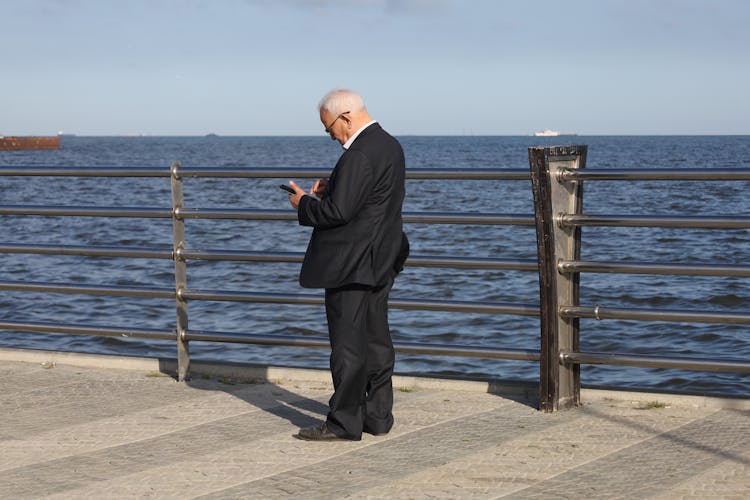 An Elderly Man In A Suit Using His Phone