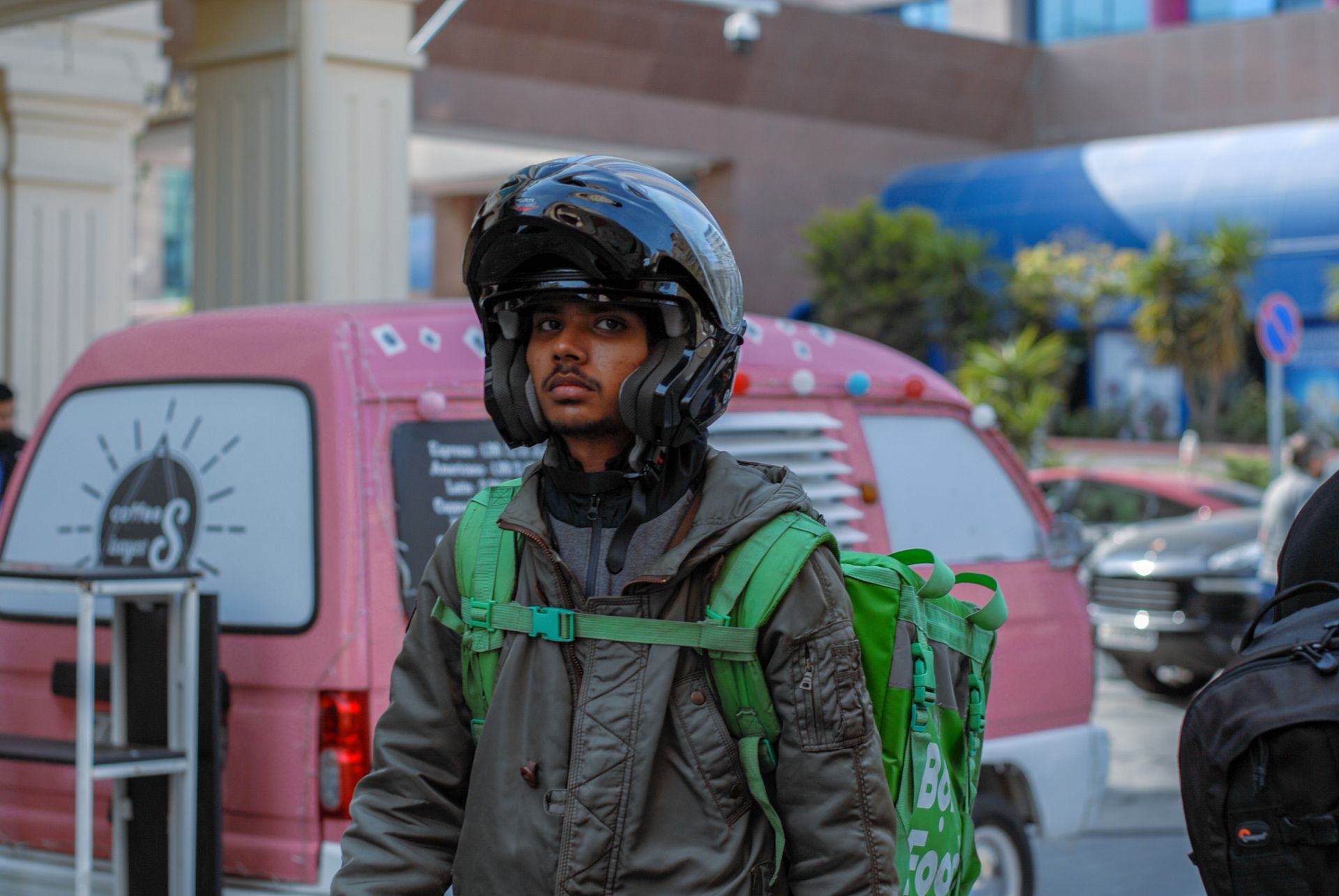 Courier on city streets with helmet and backpack, ready for delivery tasks.