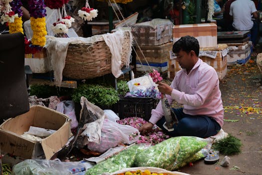 A man sorts colorful flowers in a bustling market in Ghazipur, India.