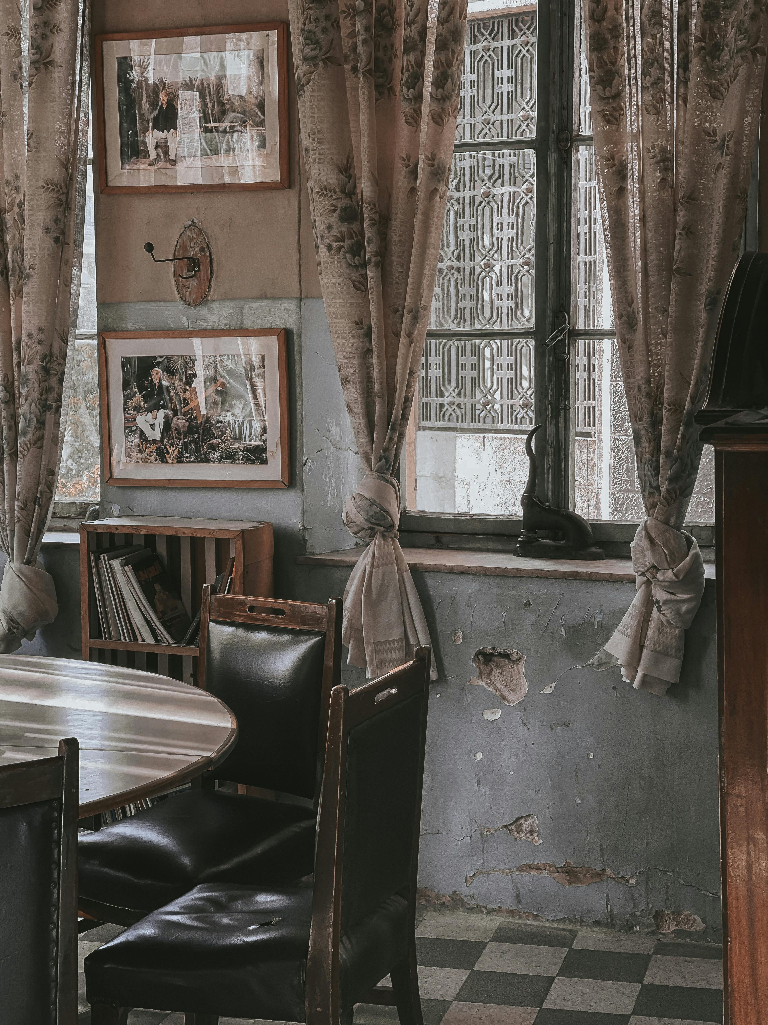 Cozy vintage room with antique furniture, art, and floral curtains creating a nostalgic ambiance.