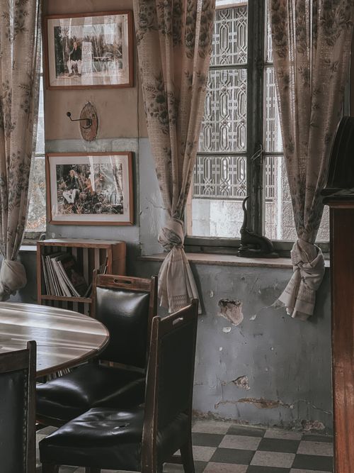 Free Cozy vintage room with antique furniture, art, and floral curtains creating a nostalgic ambiance. Stock Photo