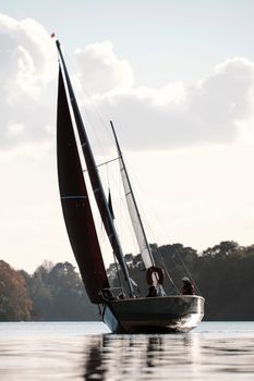 Sailboat navigating the Erdre River in autumn, near Sucé-sur-Erdre, France.