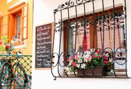 A picturesque window in Hallstatt adorned with flowers and a chalkboard menu, exuding European charm.