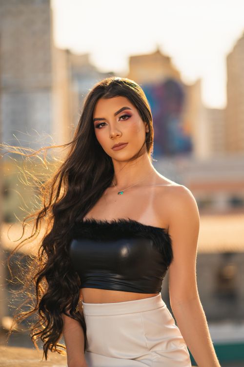 Free Portrait of a woman in a black crop top with urban background and sunset lighting. Stock Photo