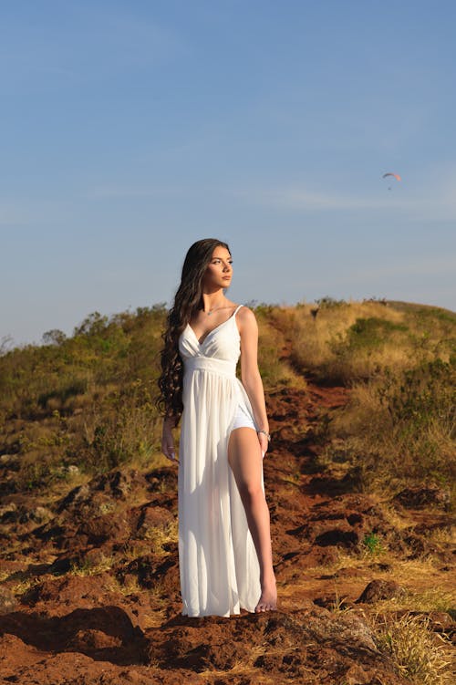 Woman in Long White Dress on Top of Hill
