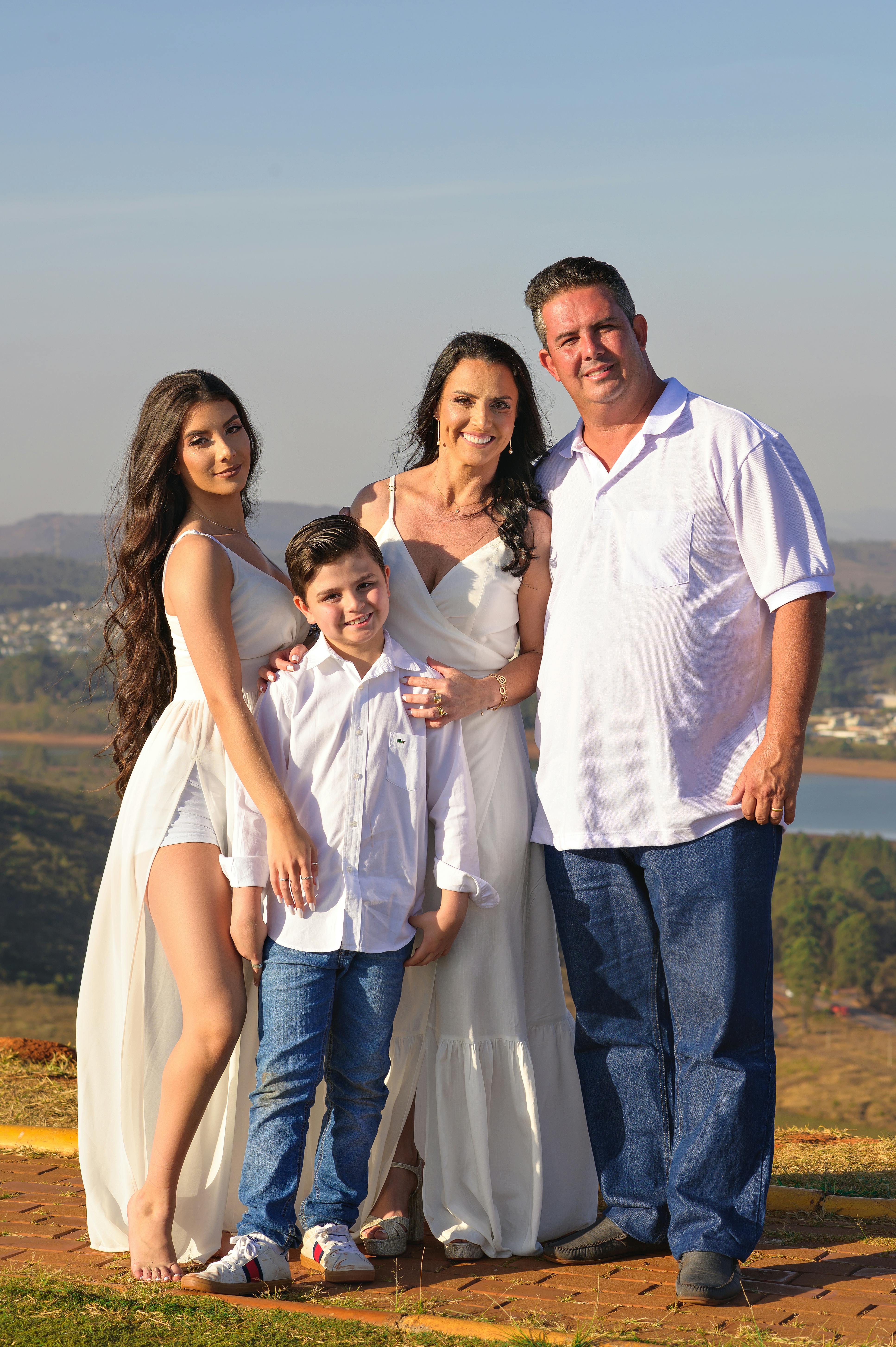 A family of four posing outdoors in a scenic background with clear skies.