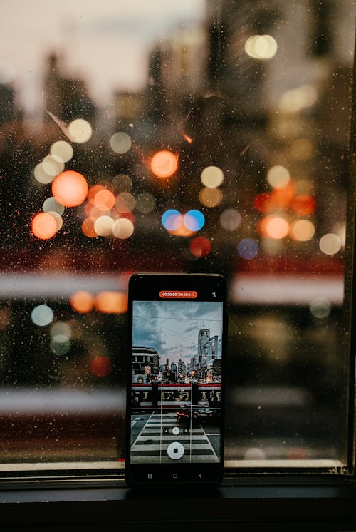 Smart Phone Recording a Video of a City Street Through a Wet Window