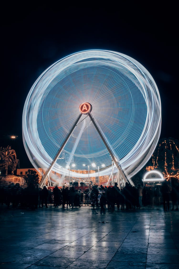 People Around Ferris Wheel In City At Night