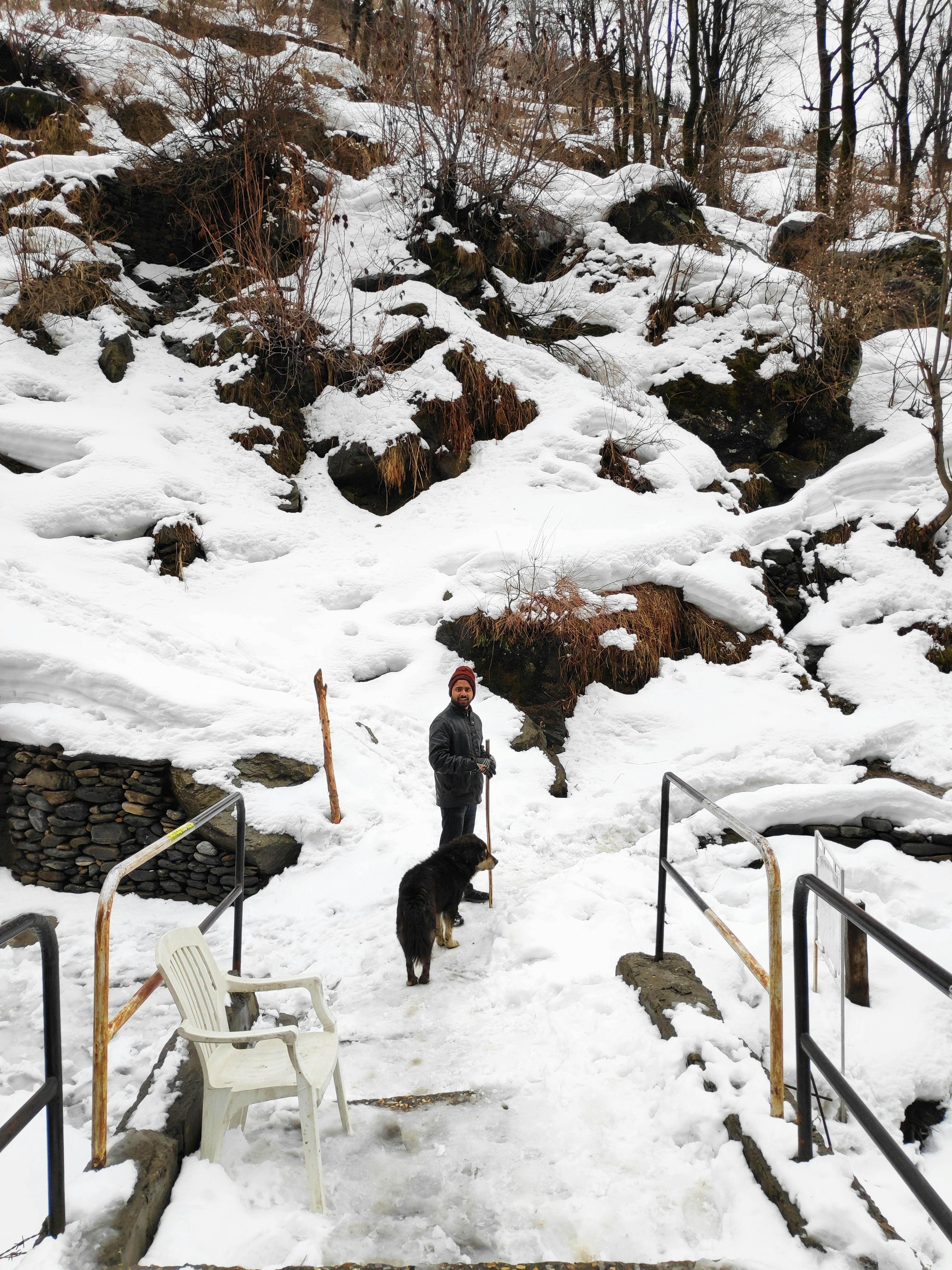 man and dog walking through snow covered mountain path