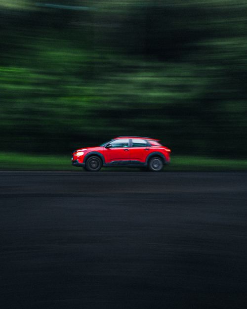 Free Red car in motion blur driving on a green-lined highway, depicting speed and movement. Stock Photo