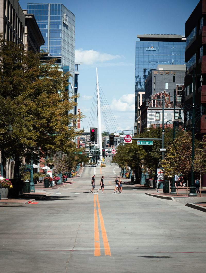 People crossing a street with the Denver Millennium Bridge in the distance