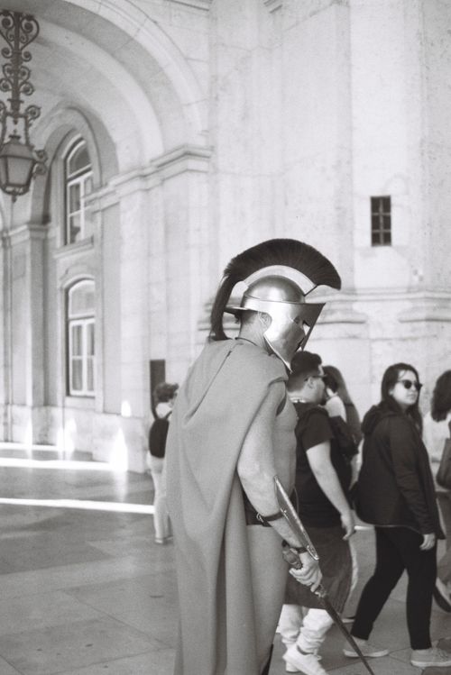 Free A street performer dressed as a Roman gladiator in a Lisbon archway captivates tourists. Stock Photo