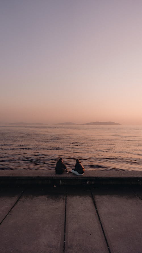 Women Sitting on a Pier at Sunset