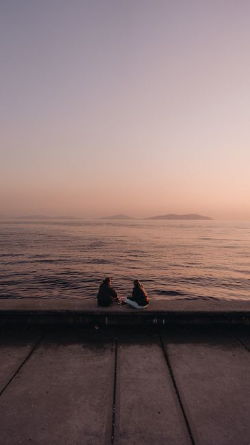 People sitting on a pier enjoying a beautiful sunset by the sea in Istanbul, Türkiye.