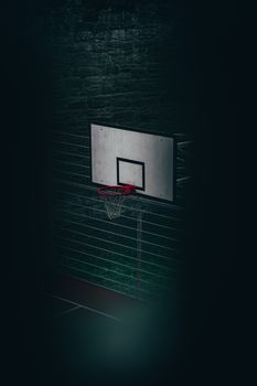 A dimly lit basketball hoop in an urban setting, capturing the essence of city sports at night.