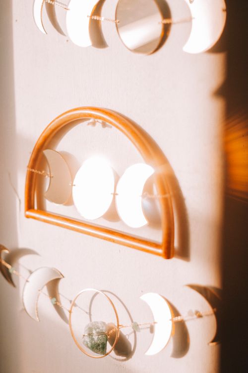 Free Elegant crescent and full moon wall hangings lit by warm sunlight, creating a serene decor piece. Stock Photo