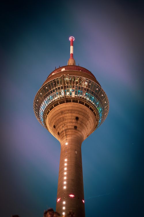 Free A striking low-angle shot of the illuminated Rheinturm in Düsseldorf at night. Stock Photo