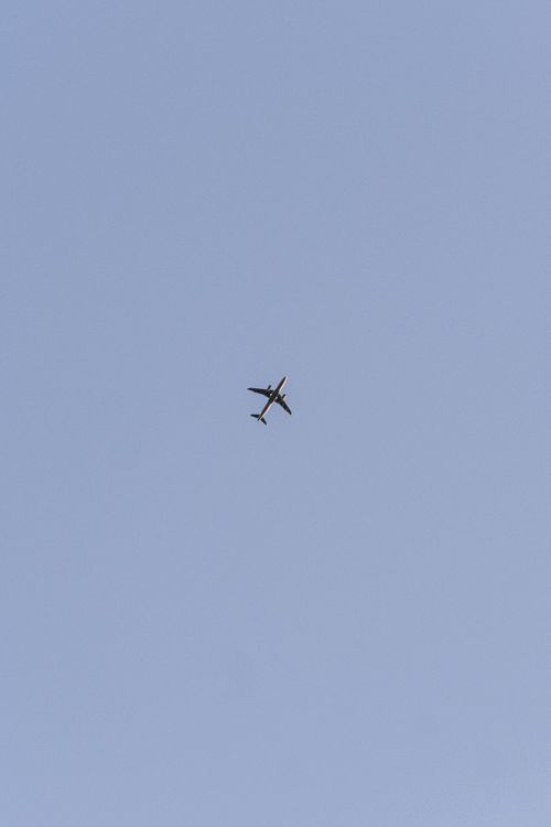 Free A lone airplane soars high in the clear blue sky, capturing the essence of flight. Stock Photo