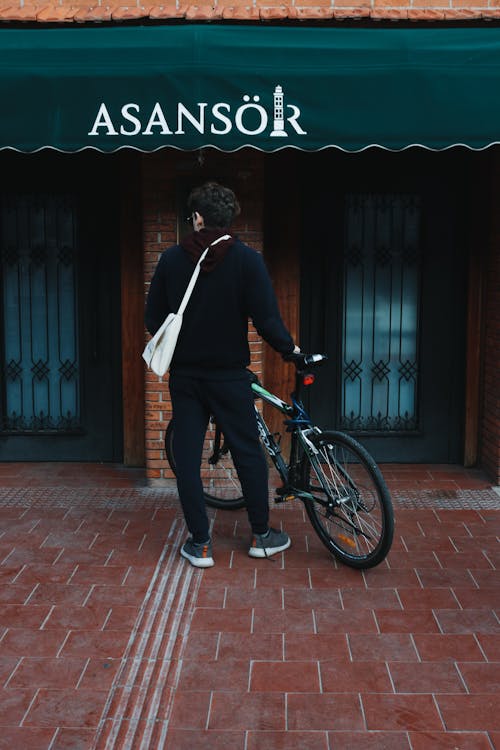 Free Man with a Bicycle Standing Outside of a Building  Stock Photo