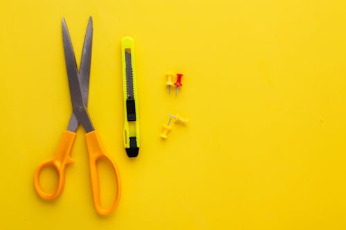 Scissors and Pins on a Yellow Background