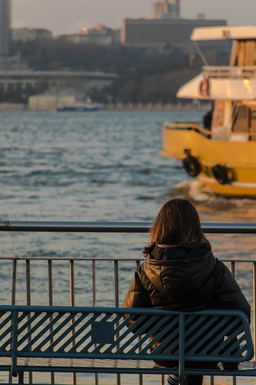 Woman Sitting on Bench with View on Ferry