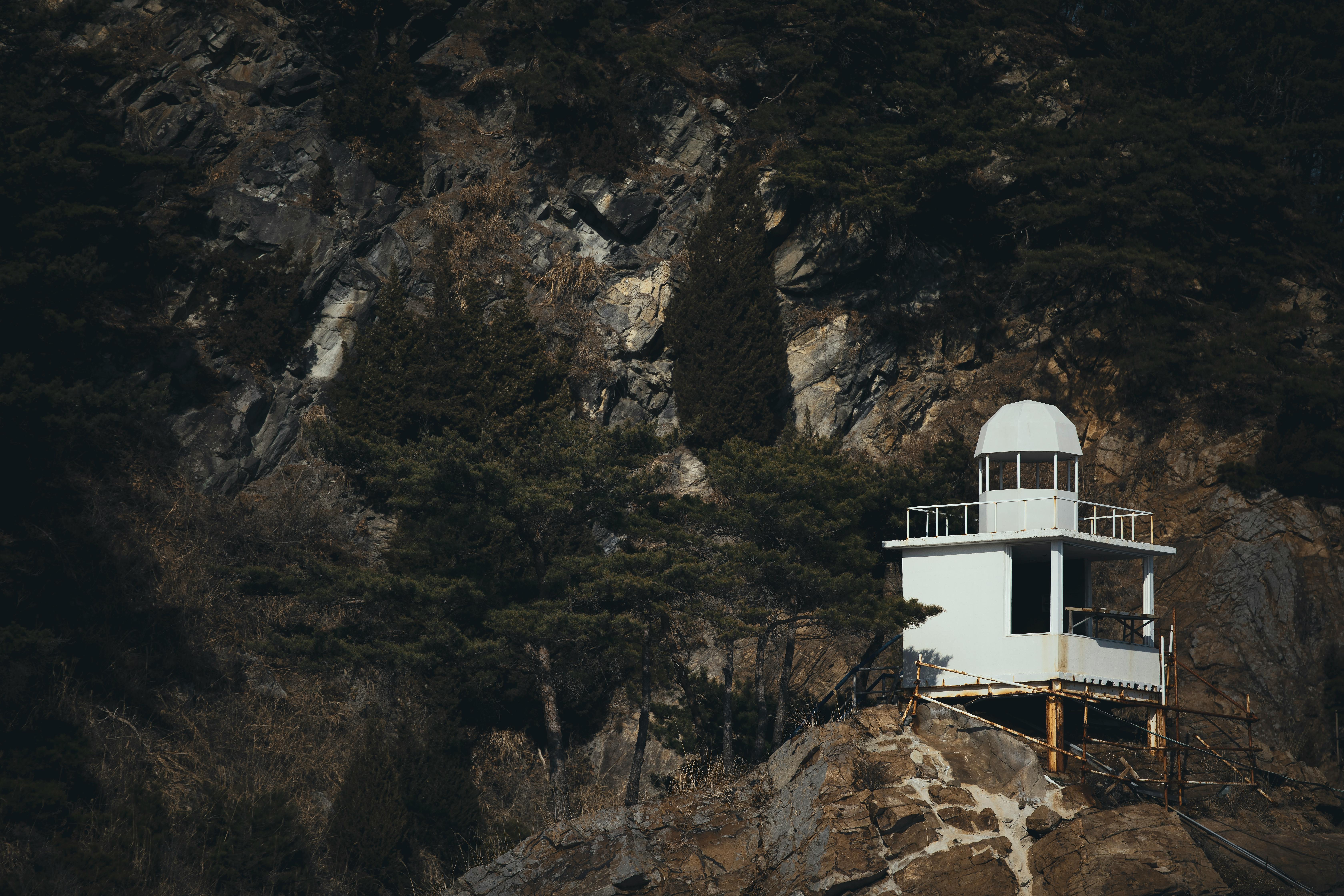 White observatory on a rocky cliff surrounded by trees in Gangneung, South Korea.