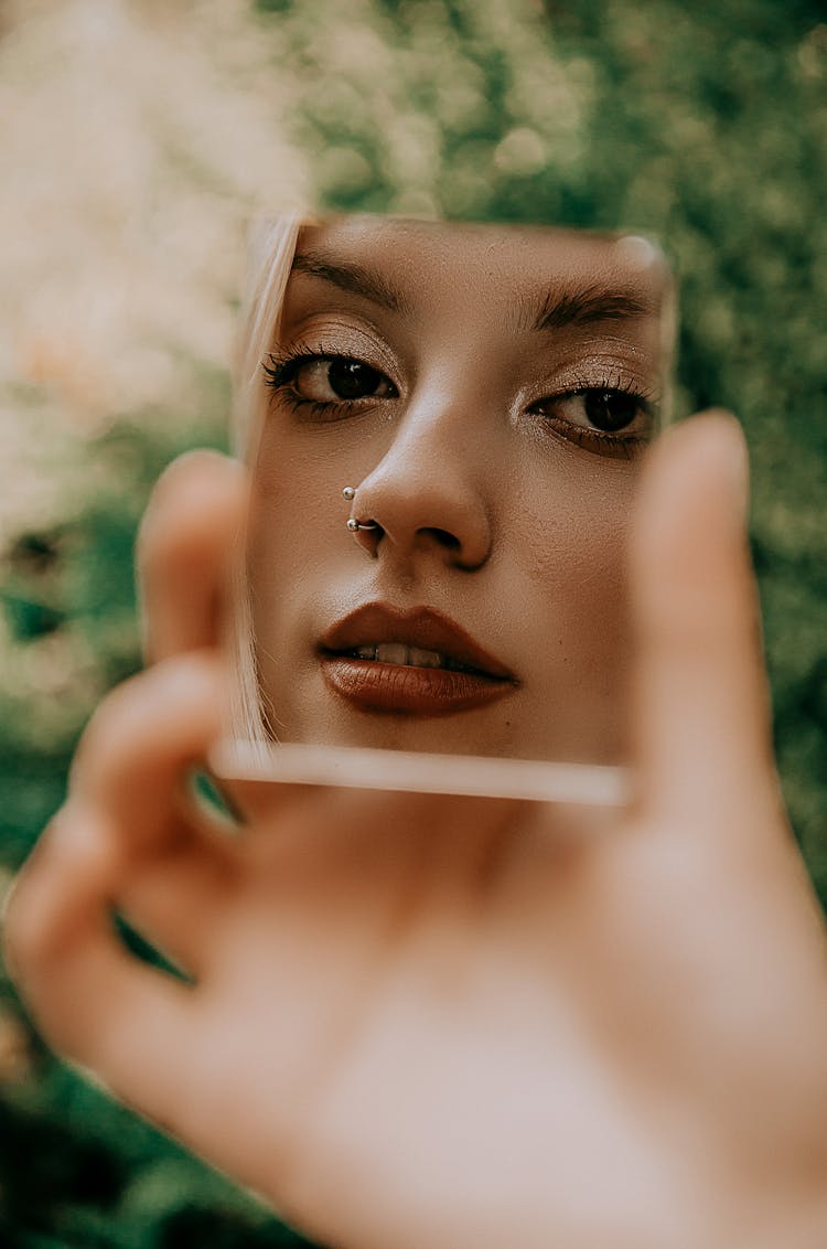 Woman Holding A Small Mirror With Her Face Reflection 